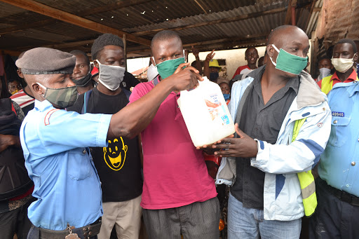 Police officers give face sanitizer and facemasks to boda boda riders in Kisumu Ndogo and Mnazi mmoja slums