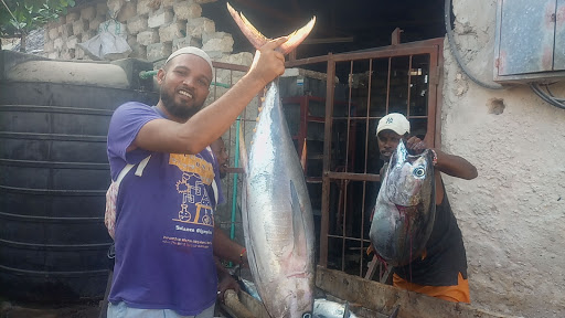 A local fisherman displays a large tuna that was part of their catch.