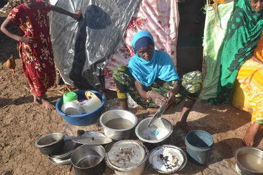 A flood victim washes her dishes  at Manono IDP camp in Tanadelta sub county after their homes were swept away by floods on May 30