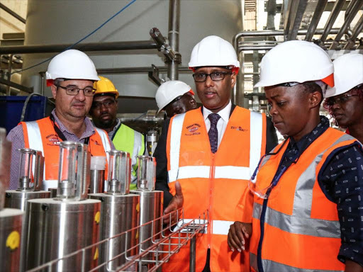 Diageo Project Manager Retief Steyn (L) explains the bottling process to Industrialisation CS Adan Mohamed at the Kisumu plant. With them is EABL Head of Sustainability Jean Kiarie Ngumo, April 23, 2018. /COURTESY