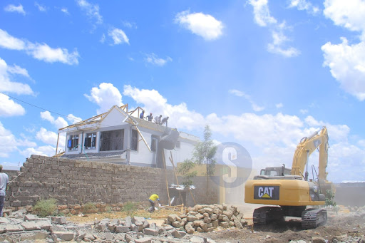 Residents try to salvage a water tank as a bulldozer moves in to demolition a house on the disputed Portland land in Athi River on October 15, 2023.