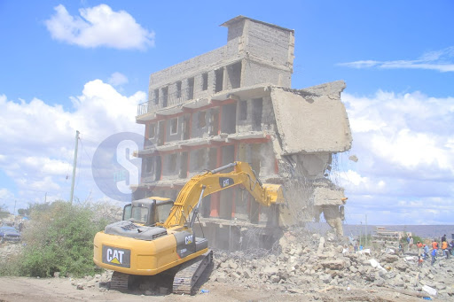 A bulldozer brings down a building on the disputed Portland land in Athi River on October 15, 2023.