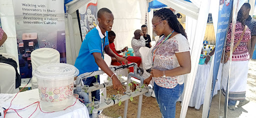 Technical University of Mombasa student Edison Jefwa explains the operations of a hydroponic system to a visitor at the Pwani Innovation Week at Swahili Pot Hub