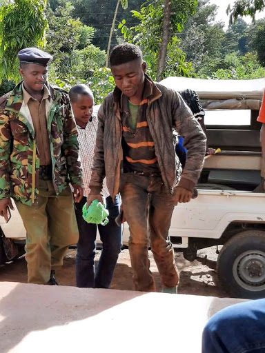 Police officer escort Musyoka Kavoi to Kangundo police station after being arrested.