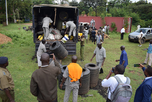 Some inmates offload conatiners with changaa and some raw materials from a police lorry after security officers nabbed them in Rangwe constituency on November 21,2023.