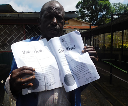 Simeon Irware shows the Star some of his tittle deeds on February 26. They are of a land he claims was taken away by individuals with police help.